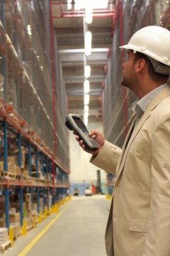 An inspector with scanner in a factory maintaining stocks of finished products on the shelves in a storeroom.